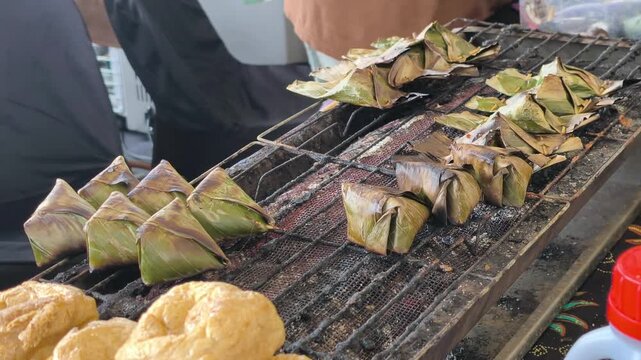 Traditional Terengganu sata fish snacks grill over hot charcoal embers. Wrapped in banana leaves, the seasoned fish paste cooks slowly to perfection.