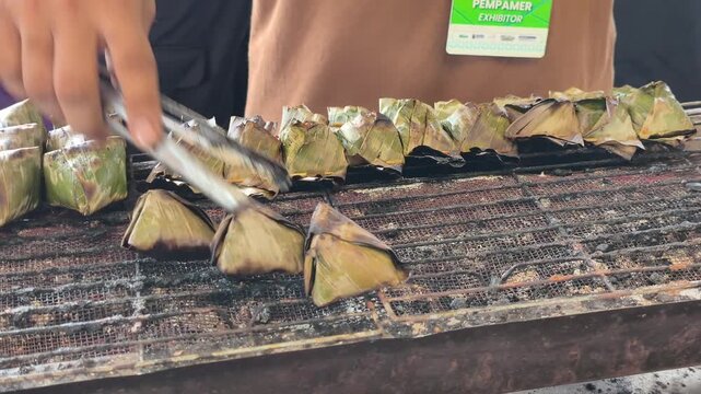Traditional Terengganu sata fish snacks grill over hot charcoal embers. Wrapped in banana leaves, the seasoned fish paste cooks slowly to perfection.