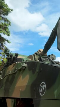A detailed lowangle shot of a military armored personnel carrier featuring camouflage paint, a gun turret, and heavyduty wheels under a blue sky. Suitable for defense and security content.
