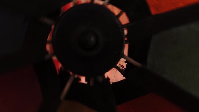 Abstract close-up of a dark, spinning object with glowing orange accents, motion blur, dark background