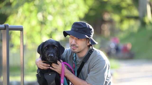 [春～夏イメージ]大型犬と顔を寄せてカメラ目線で笑顔の日本人男性、犬と飼い主の絆、信頼やコミュニケーションイメージの動画