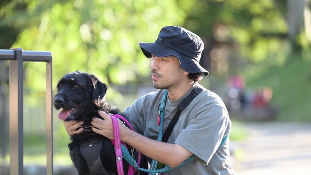 [春～夏イメージ、スローモーション]大型犬と顔を寄せてカメラ目線で笑顔の日本人男性、犬と飼い主の絆、信頼やコミュニケーションイメージの動画