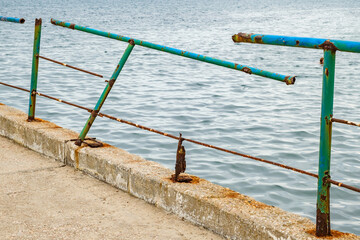 Fototapeta premium stone pier in sea with old rusty railings