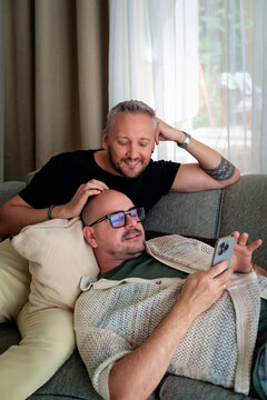 Homosexual couple relaxing on sofa at home