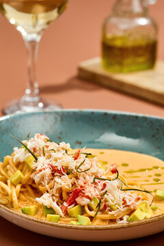 Crab pasta with fluffy shredded seafood, creamy bisque and avocado cubes in a blue bowl for menu and recipe