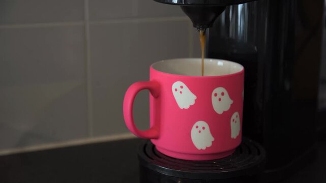 Coffee pours into a bright pink Halloween ghost mug, combining seasonal lifestyle, colorful kitchen and coffee imagery for home, office and hospitality settings.