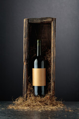 Obraz premium Bottle of red wine in old wooden box on a black background.