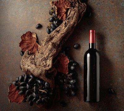 Bottle of red wine with blue grapes on a rusty background.