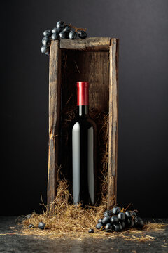 Bottle of red wine in old wooden box on a black background.