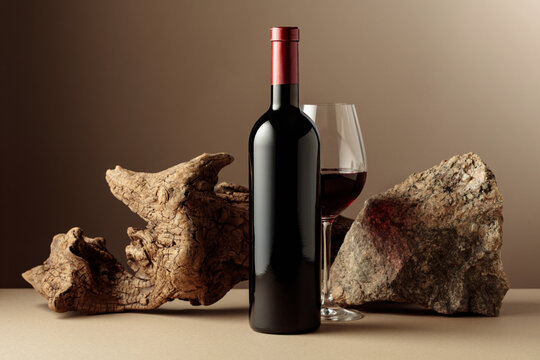 Glass and bottle of red wine with old driftwood and a piece of granite rock.
