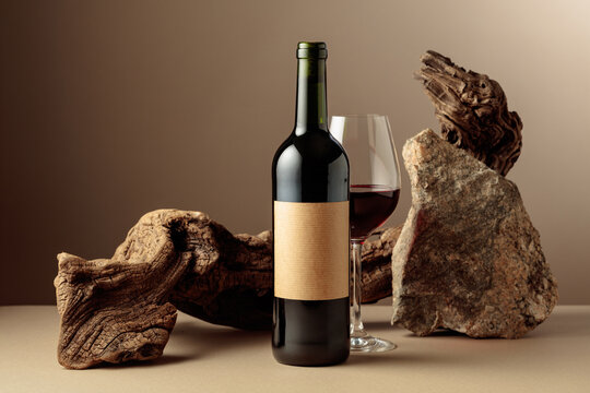 Red wine with old driftwood and a piece of granite rock on a beige background.