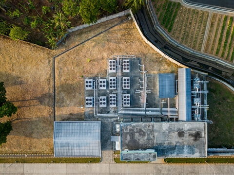 Aerial view of an industrial facility featuring multiple HVAC cooling units and piping systems, situated near agricultural fields and trees in Semarang Regency, Central Java, Indonesia.
