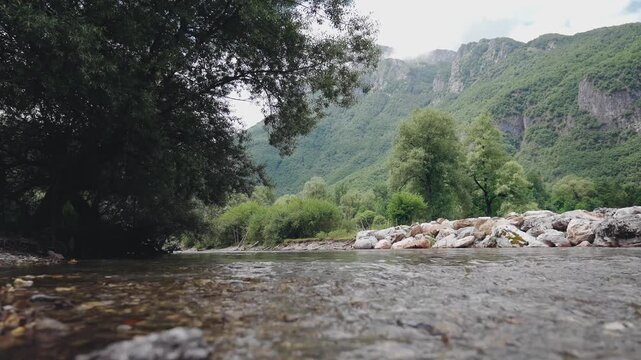 Low-angle view of a mountain river flowing through a scenic valley surrounded by majestic mountains, capturing pristine nature, wilderness and the peaceful beauty of a mountain landscape.