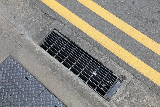 Storm drain metal grate in a street in Singapore City.