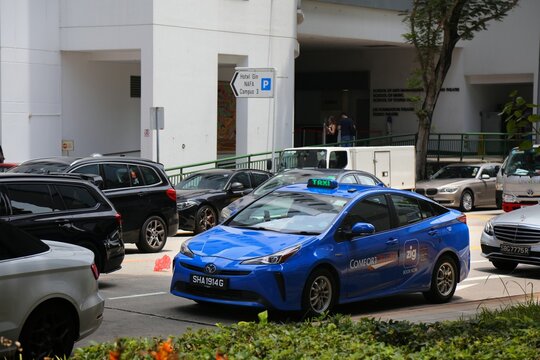 SINGAPORE CITY, SINGAPORE - MARCH 11, 2024: Toyota taxi cab drives in Singapore City traffic. The taxi is operated by ComfortDelGro company and is bookable in Zig app.