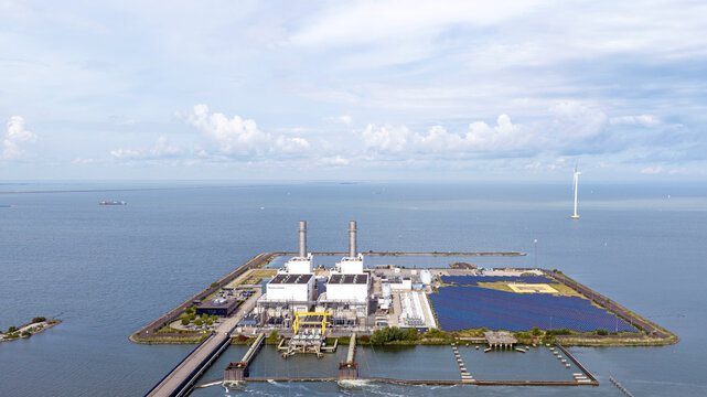 Aerial view of the Maxima power plant with its industrial chimneys and large solar panel array situated on an artificial island in the Markermeer, Lelystad, Flevoland, Netherlands.