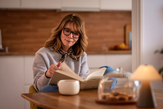 Confident woman with a book sitting at a table and reading