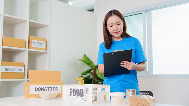 Asian female volunteer writing on clipboard at community donation center