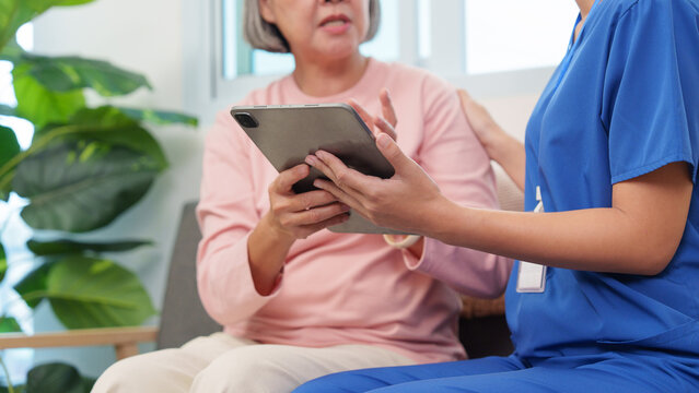 Close up of senior woman holding digital tablet with nurse support at home