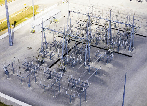 Aerial view of the electrical substation at a cell manufacturing plant, featuring metal structures, power lines, and gravel ground in Spring Hill, TN, United States.