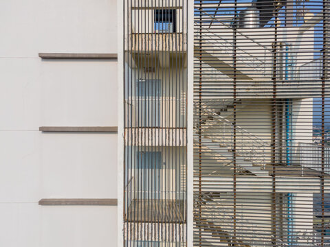 Aerial view of a modern building facade featuring a stairwell enclosed by metal louvers, concrete walls, and visible doors in Purwokerto, Central Java, Indonesia.