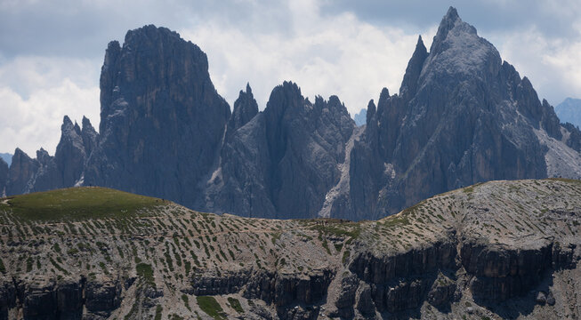Majestic scenery of rough mountain ridge near grassy hills Tre Cime, Dolomites Italy