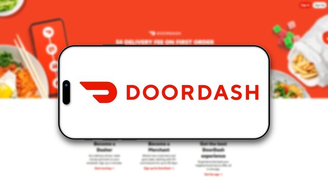 Izmir, Turkey - 30 Sep 2026: DoorDash logo on a smartphone screen in front of the blurred DoorDash website, the American food delivery platform for online ordering and takeaway