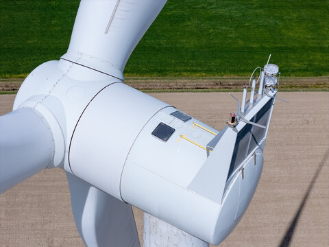 Aerial view of a white wind turbine nacelle with blades and technical equipment against a background of agricultural fields in Lakeshore, Ontario, Canada.