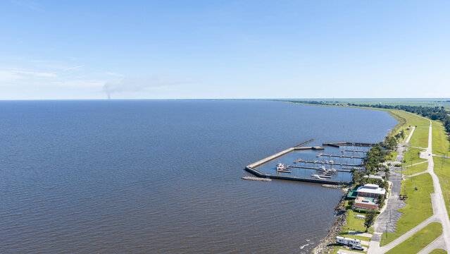 Aerial view of the marina at Lake Okeechobee with boats docked, a grassy levee, and clear blue sky in Pahokee, Florida, United States.