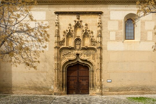 Granada's Royal Chapel entrance featuring intricate Isabelline Gothic architectural details with an ornate carved stone doorway and historic wooden doors