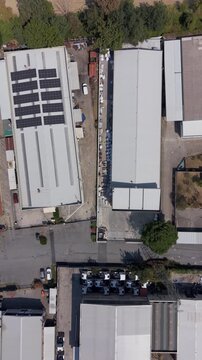 Drone footage of an industrial area showing factory buildings, warehouses, rooftop solar panels and parked trucks. Suitable for manufacturing, logistics, infrastructure and business content