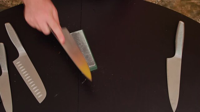 Man sharpening knife on sharpening stone at home. Close-up of routine kitchen tool maintenance