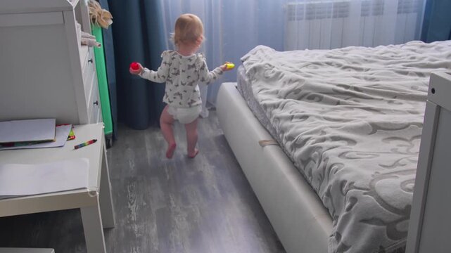 Baby girl learning to walk and taking first independent steps in home interior. Early childhood milestone concept