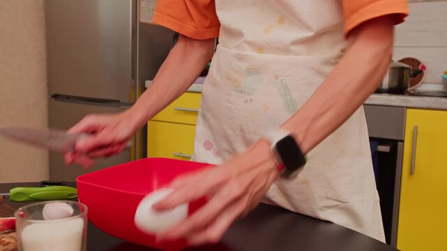 Woman cracking eggs while preparing homemade batter. Close-up of hands during everyday home cooking