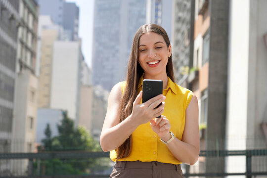 Portrait of young business woman using mobile app in Sao Paulo city street, Brazil
