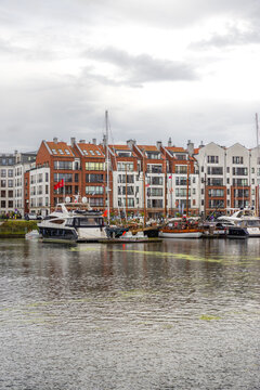 Gdansk, Poland - 05 September 2026: View of yachts and boats moored along the Motlawa riverfront with modern apartment buildings in the background under a cloudy sky.