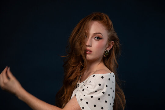 Woman in a polka dot top posing with arm raised 
