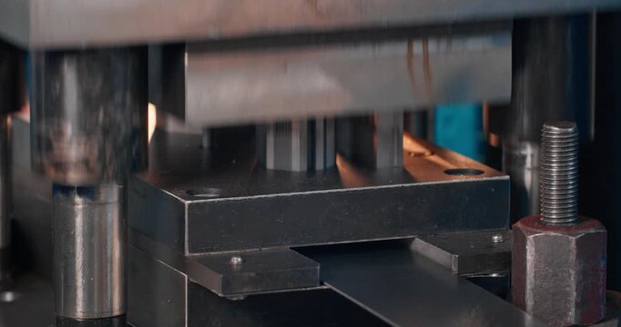 Mechanical stamping press in operation at metalworking shop. Close-up of metal blanking equipment during factory production