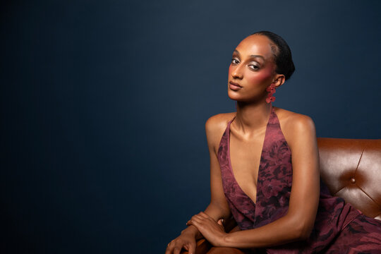 Woman in burgundy dress and red earrings on blue background