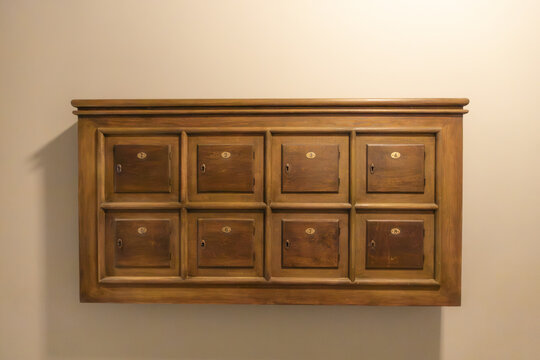 View of a vintage wooden cabinet with eight numbered compartments mounted on a plain wall in Gdansk, Pomeranian Voivodeshi, Poland.