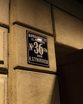 View of a historic building sign for Komisariat XVI on ul. Pulawska 36, Dom K. Szymanskiego, mounted on a textured stone wall in Gdansk, Pomeranian Voivodeship, Poland.