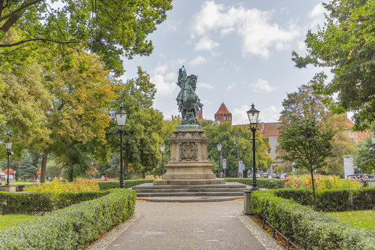 View of the King John III Sobieski monument surrounded by lush trees, manicured hedges, and flower beds in a public park in Gdansk, Pomeranian Voivodeship, Poland.