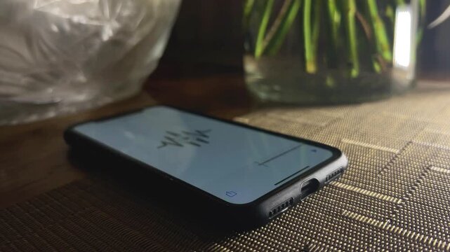 Close-up shot of a hand turning off an audiobook app on a smartphone and placing a wireless earbud on the table. Ideal for digital media and technology visuals.