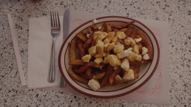 Montreal Canada poutine plate crispy fries topped with cheese curds and brown gravy, authentic Quebec comfort food in diner setting.