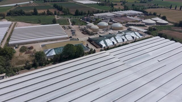 Aerial view of an agricultural complex in northern Italy combining cattle farming, biomethane production, vegetable greenhouses and rooftop solar panels as part of sustainable agriculture.