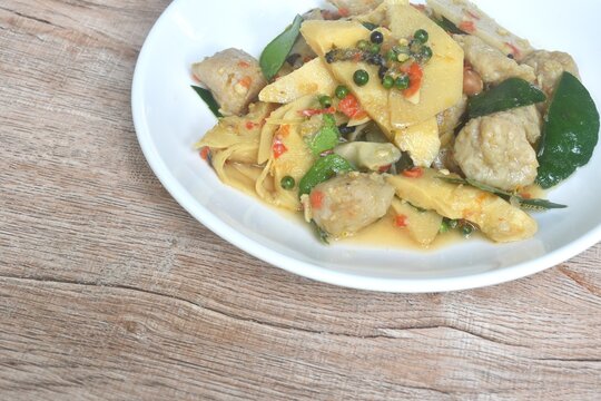 spicy stir fried bamboo shoot and clown featherback fish ball with curry couple basil topping peper on plate