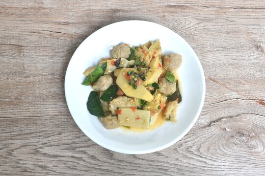 spicy stir fried bamboo shoot and clown featherback fish ball with curry couple basil topping peper on plate