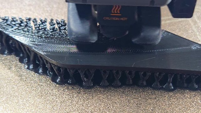 Macro Shot of 3D Printer Extruder Head Printing Black Plastic Layer by Layer in Additive Manufacturing Process