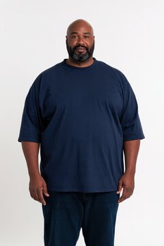Single-subject photograph of a dignified Black man in casual attire against a white studio background