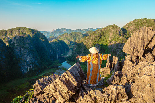 A young woman admires the  panorama of limestone rocks from Hang Mua Mountain. Ninh Binh Province, Vietnam.